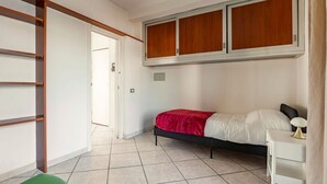 Un dormitorio con cama, escritorio, armario y puerta que da a otra habitación.