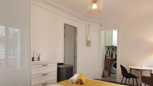A hotel room with a bed, a desk, a chair, a wardrobe, and a bathroom visible through an open door.
