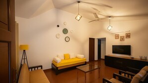 Un salon moderne avec un canapé, une table basse, un téléviseur et un ventilateur de plafond.