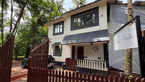 Une maison à deux étages, avec une façade noire et blanche, un porche couvert et une enseigne indiquant « Casa Verde ».