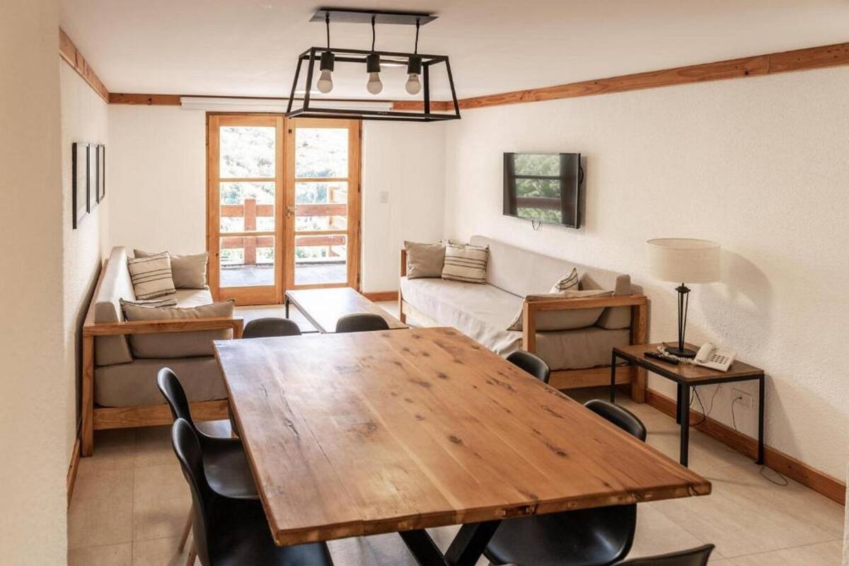 A cozy dining area with a wooden table and chairs, a sofa, and a small side table with a lamp.