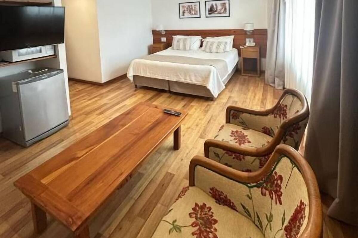 A hotel room with a bed, a desk, a TV, and two chairs.