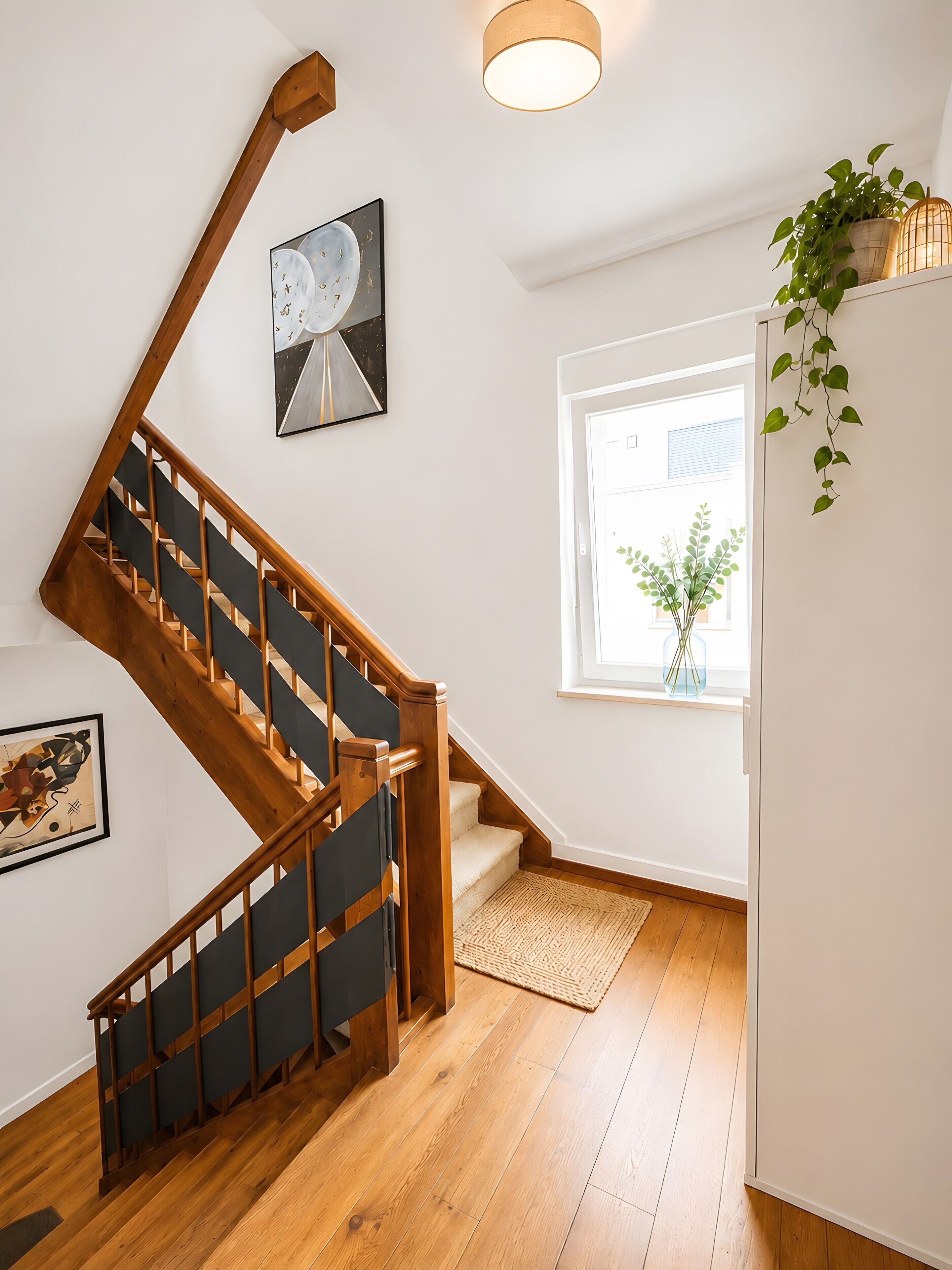 A wooden staircase with a black handrail leading to a landing.