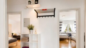 Ein modernes Interieur mit einer weißen Regalkonstruktion, einer Kleiderstange und einem Bett mit Blick zum Fenster.