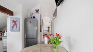 Een keuken met een koelkast, een eettafel met placemats en een vaas met tulpen.