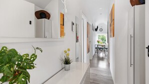 Een moderne hal met een kamerplant, een spiegel en een deur naar een eetruimte.