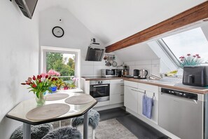 Una cocina moderna con tragaluces, un comedor con mesa y sillas, y vistas a zonas verdes.