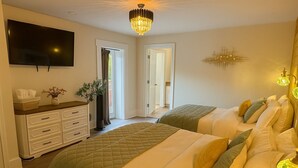 A bedroom with two beds, a dresser, a TV, and a chandelier.