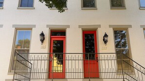 A multi-story building with white exterior walls, red doors, and black window frames.