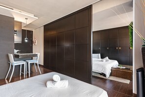 A modern hotel room with a large bed, a desk with two chairs, a dark partition wall, and a separate sleeping area with a headboard. - Apartment 'Con Vistas Al Mar' with Sea View, Wi-Fi and Air Conditioning (Marbella)