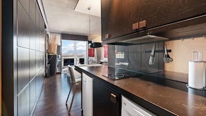 Een moderne keuken met roestvrijstalen apparatuur, een zwart aanrecht en uitzicht op de stad.