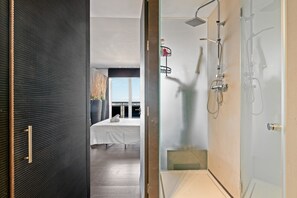 A modern hotel room with a large bed, a shower with a glass door, and a view of the city. - Apartment 'Con Vistas Al Mar' with Sea View, Wi-Fi and Air Conditioning (Marbella)