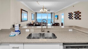 A kitchen with a double sink, granite countertops, and a view of the ocean. - Majestic Beach Towers 1-2003 (Panama City Beach)