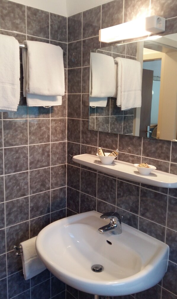 A bathroom with a white sink, a mirror, and a towel rack.