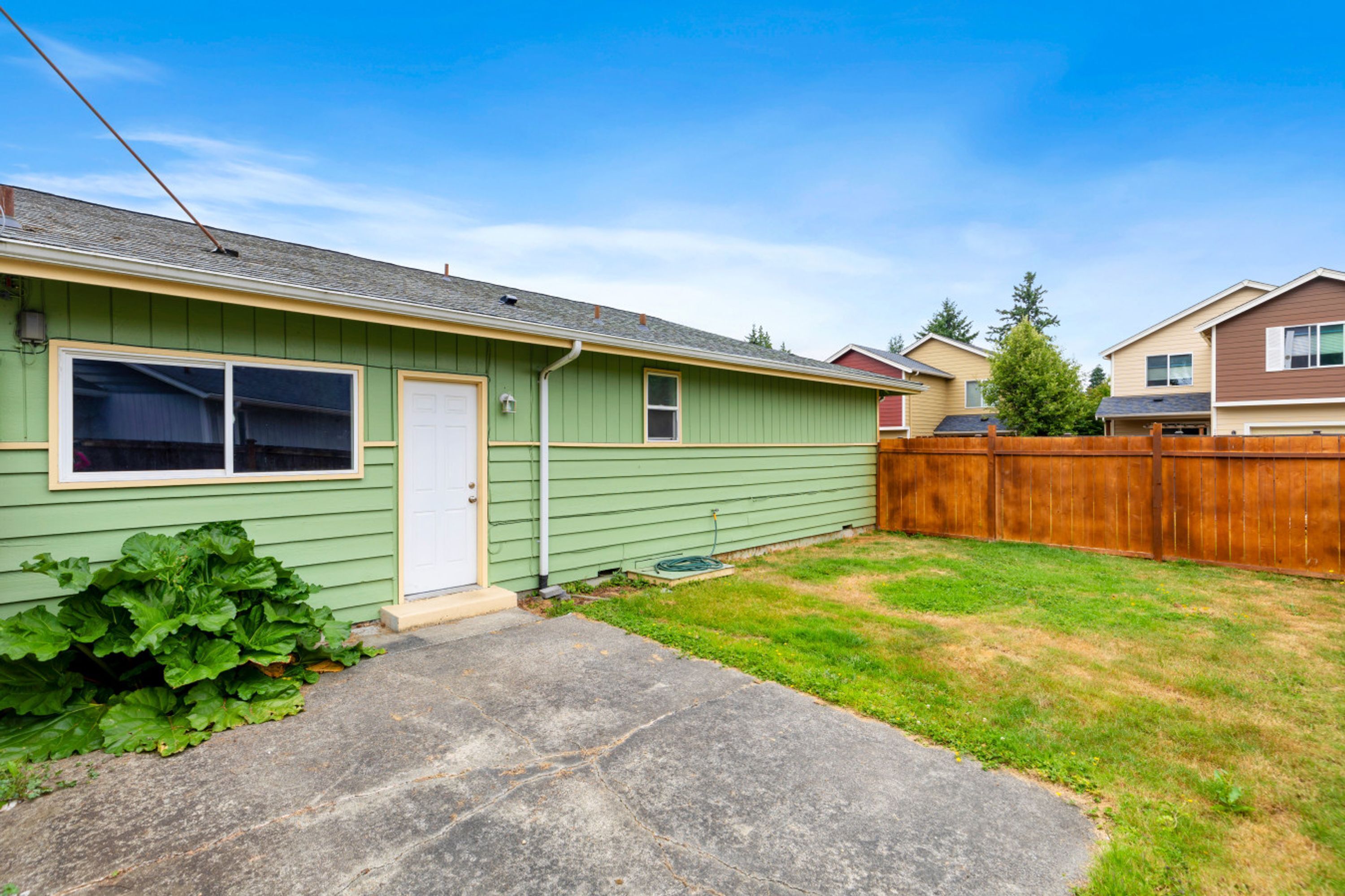 A single-story house with a green exterior, a front door, and a visible garage door.