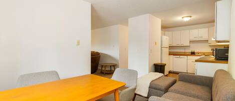 A compact living space with a dining area, a sofa set, and a kitchenette.