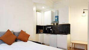 Un dormitorio moderno con cama, dos almohadas, una mesita de noche y un pequeño banco de madera.