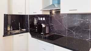 Una cocina moderna con encimeras de mármol negro, lavavajillas Bosch y cafetera.