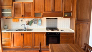 A kitchen with wooden cabinets, a stove, a sink, and a dishwasher. - P074 – Porto Recanati, apartment with garage, 50 meters from the sea (Porto Recanati)