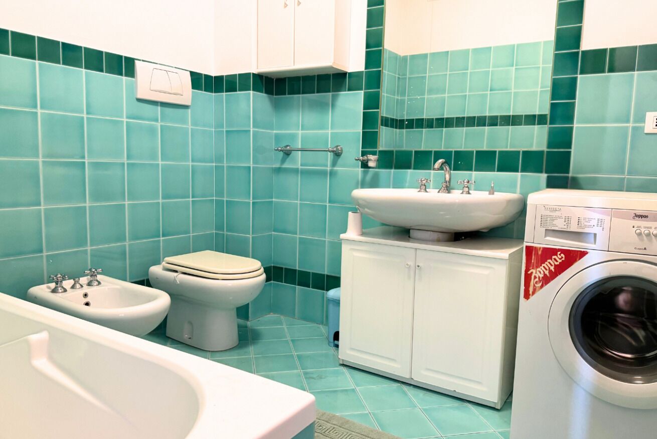 Une salle de bain équipée d’un bidet, de toilettes, d’un lavabo et d’un lave-linge.