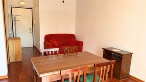 A dining area with a wooden table, green cushioned chairs, a red sofa, and a small cabinet. - P074 – Porto Recanati, apartment with garage, 50 meters from the sea (Porto Recanati)