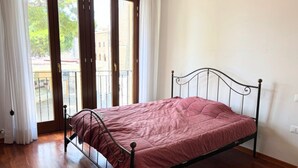 A single bed with a metal frame, a wooden floor, and a view through a glass door to the outside. - P074 – Porto Recanati, apartment with garage, 50 meters from the sea (Porto Recanati)