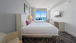 A hotel room with a large bed, a desk, and a view of the ocean.