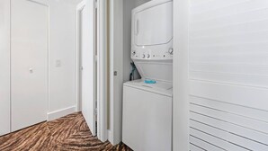 A laundry room with a washing machine and dryer, a door, and a patterned carpet.