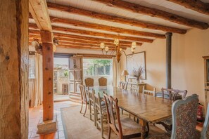A dining area with a wooden table and chairs, a chandelier, and a view of the outdoors.