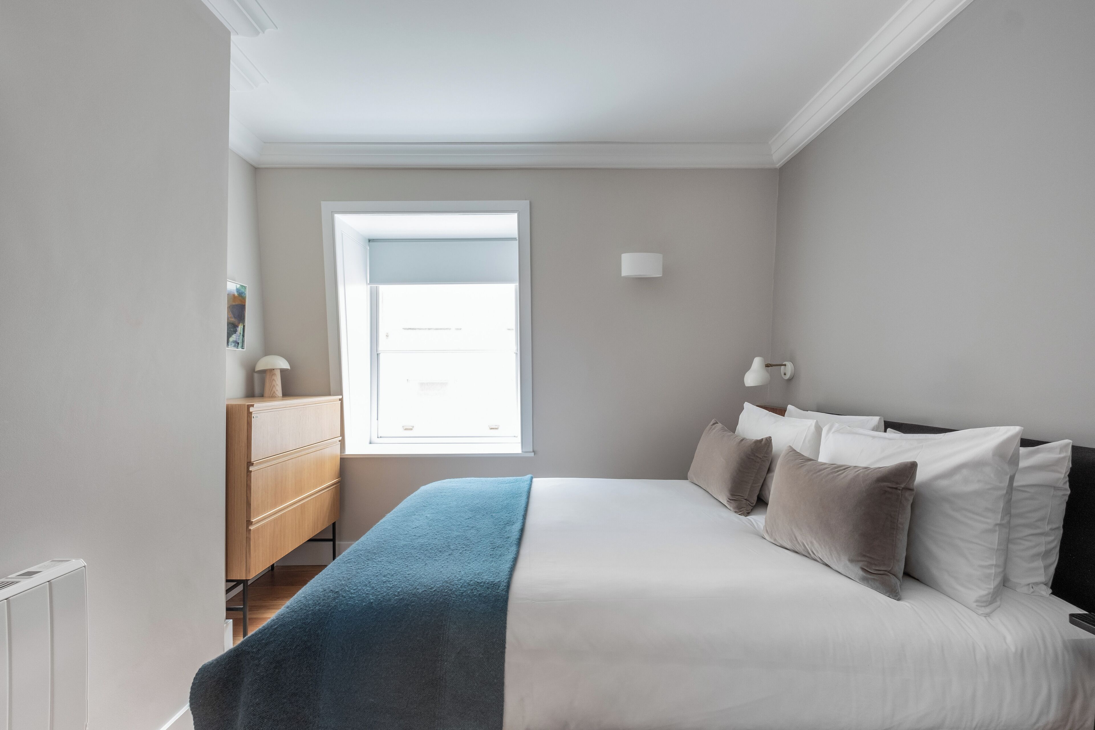Ein Schlafzimmer mit einem Bett, einem Schminktisch, einem Fenster und einer Wandleuchte.