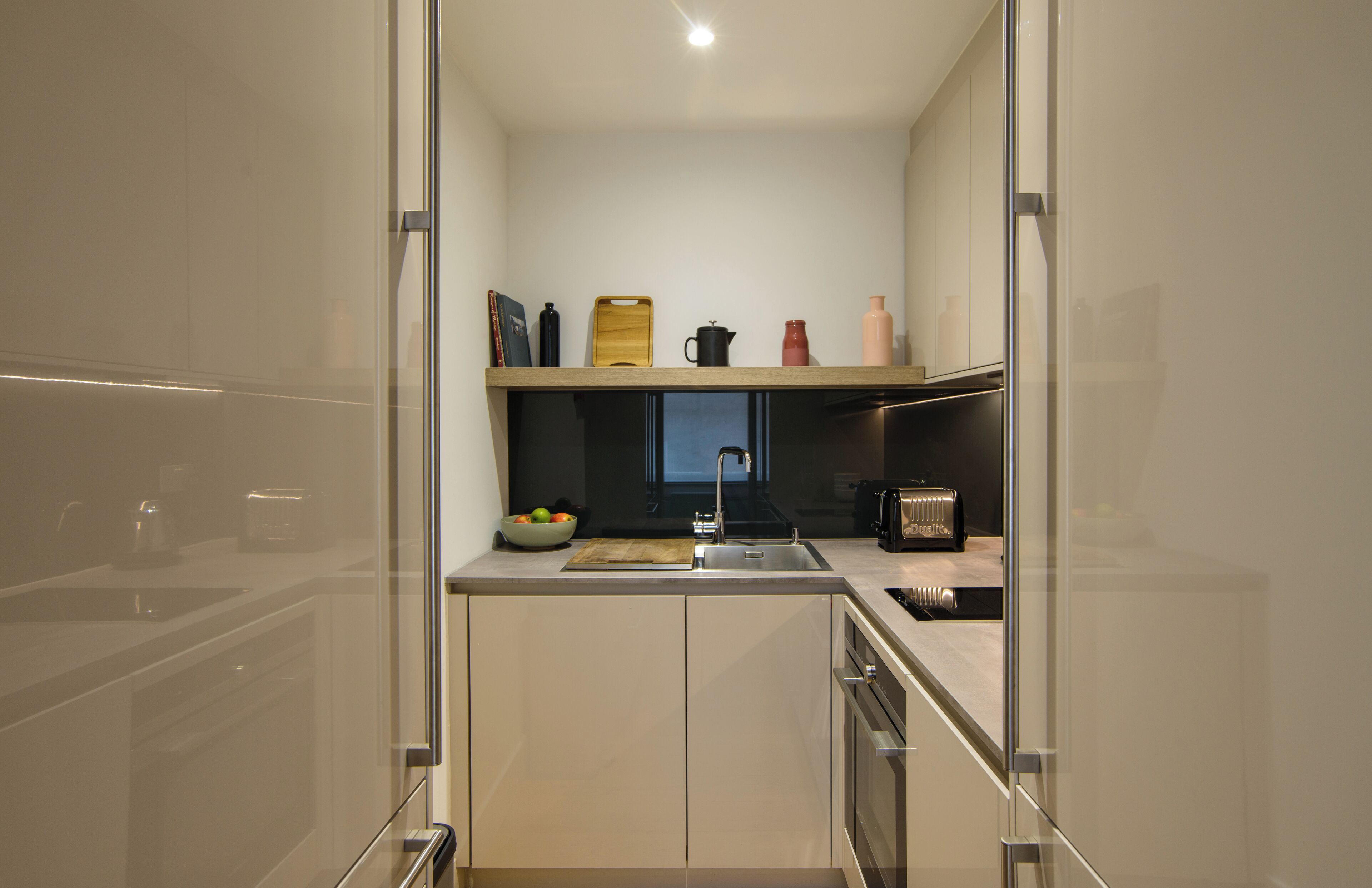 Een moderne keuken met een ingebouwde oven, een spoelbak en een aanrecht met verschillende apparaten en een fruitschaal.