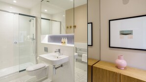 A modern bathroom with a glass shower enclosure, a white sink, and a vanity with a mirror. - Native Bank (London)