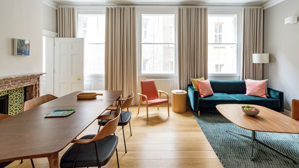 A modern living room with a wooden dining table, chairs, a sofa, and a fireplace. - Native Bank (London)