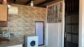 A laundry room with a washing machine, a tiled wall, and a door with a cityscape mural.