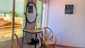 A balcony with wicker chairs, a small table, and a decorative mirror.