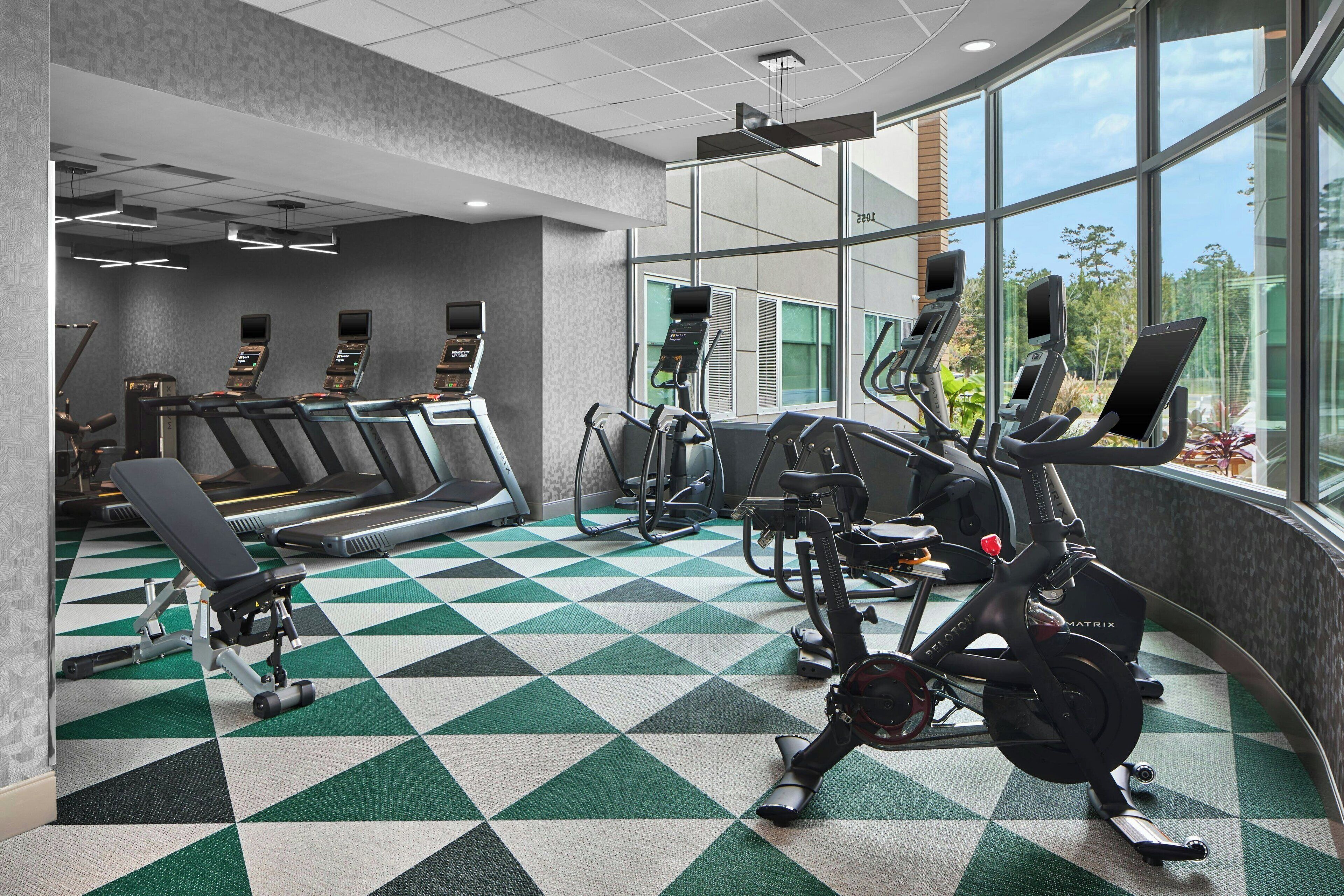 Un gimnasio con cintas de correr, elípticas y equipamiento de pesas.