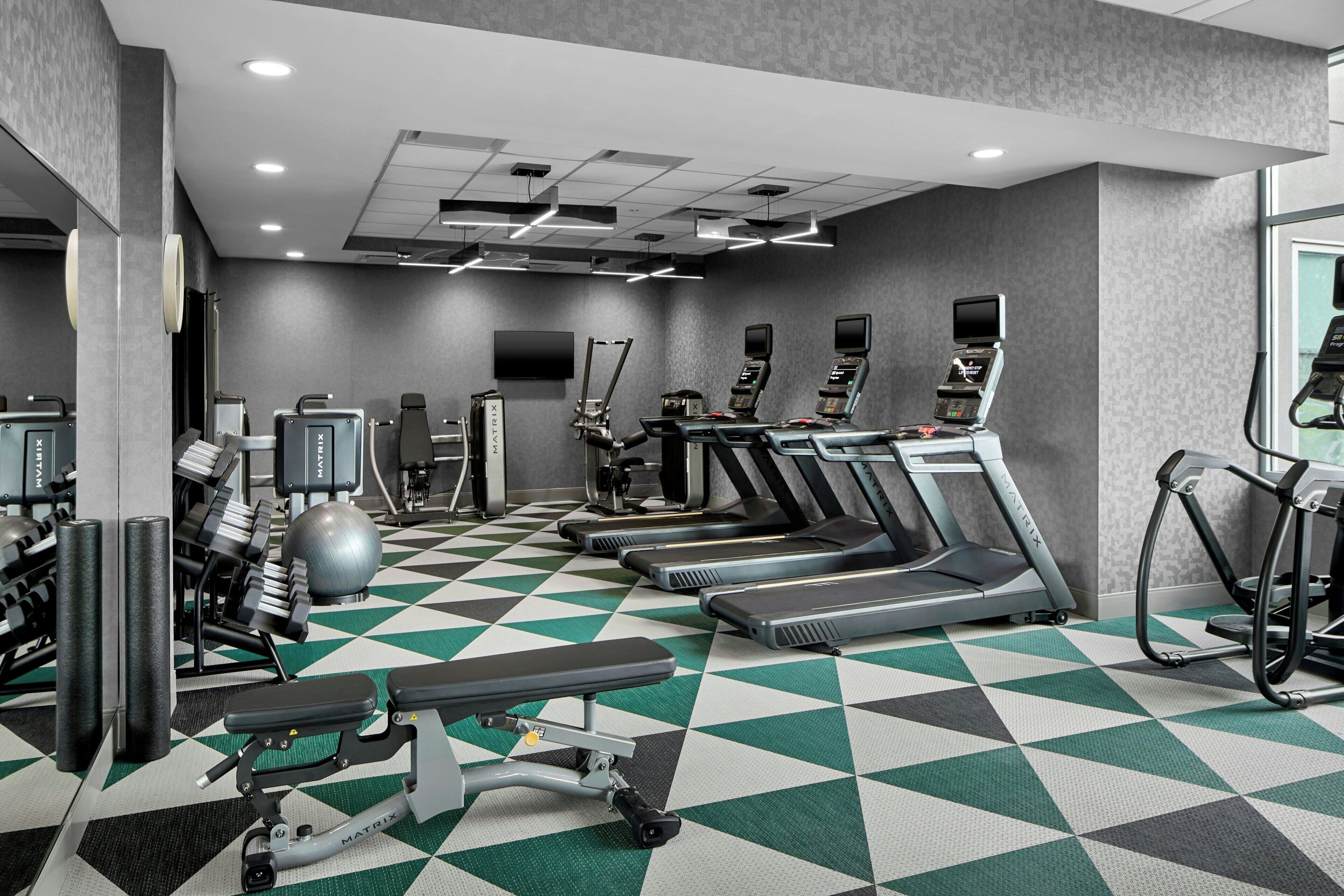 A gym with treadmills, elliptical machines, and weight equipment.