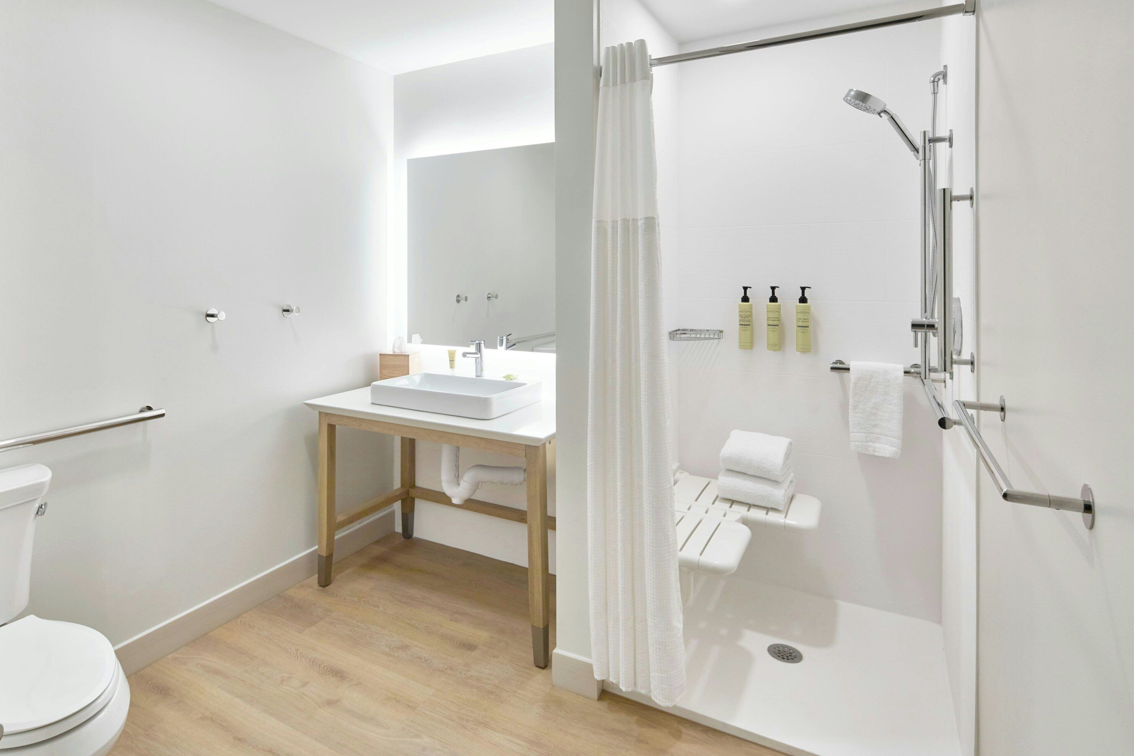 A modern bathroom with a shower, toilet, sink, and a mirror.