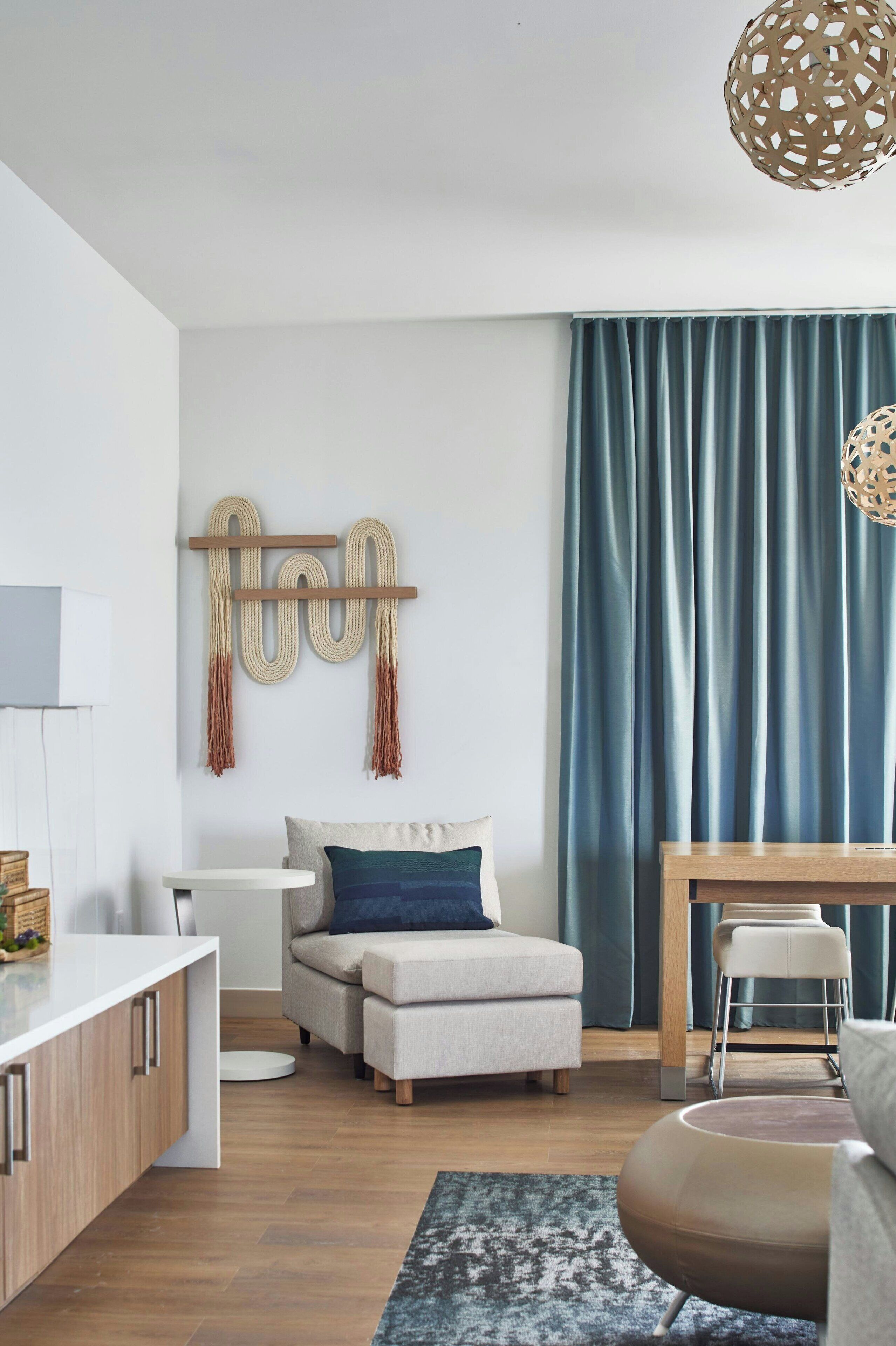 A modern living room with a sofa, a coffee table, and a dining area with a table and chairs.