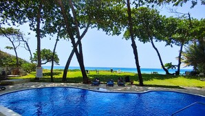 A swimming pool with lounge chairs and a view of the beach. - 2-bedroom condo in serene Perla Marina with AC, WiFi. Enjoy relaxation (Playa Perla Marina)