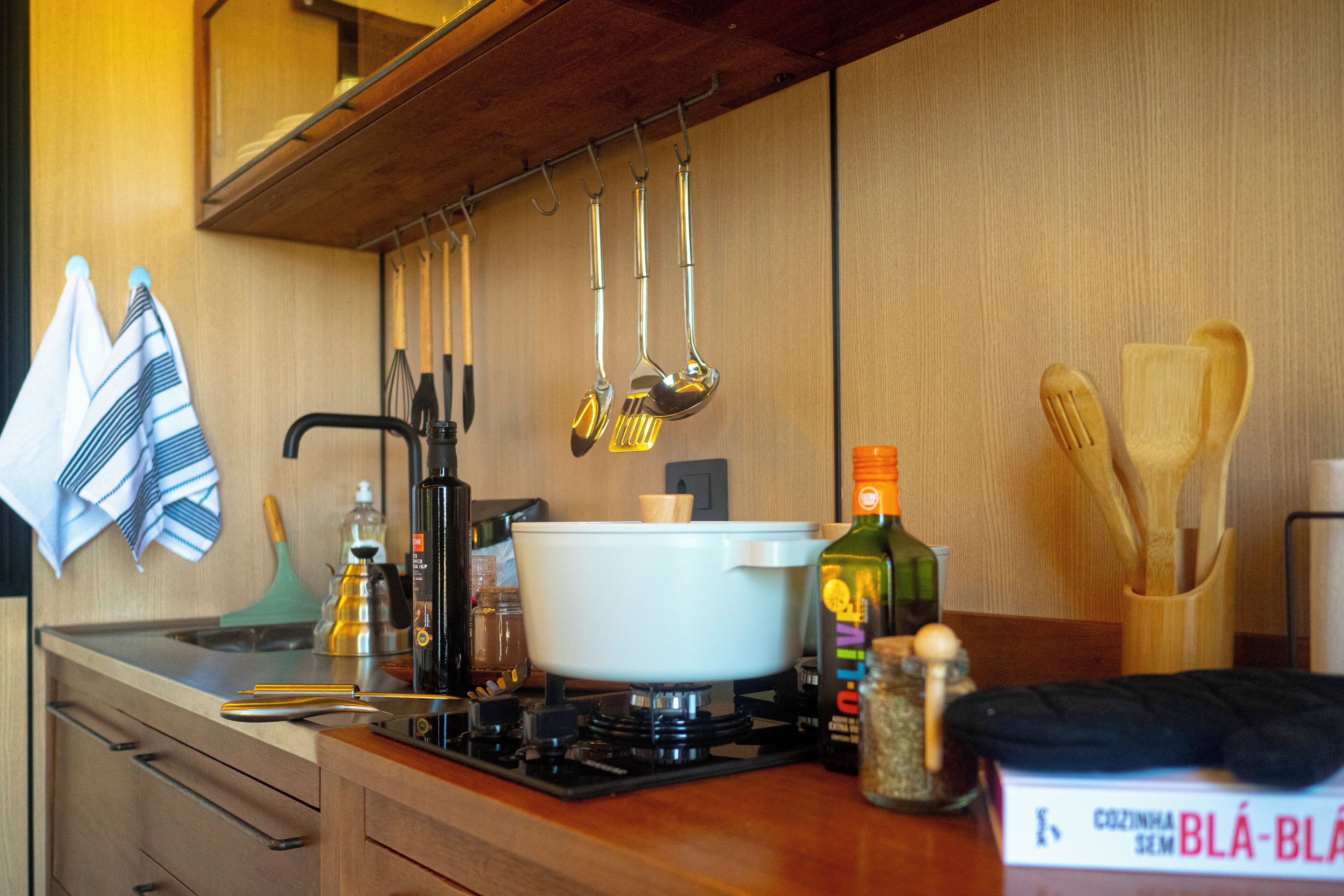 Una cocina con estufa, ollas, utensilios y un libro de cocina.