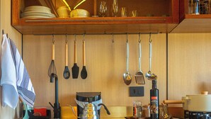 A kitchen with wooden cabinets, a hanging pot rack, and various kitchen utensils. - Nest Altar (Joanópolis)