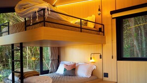 A bunk bed room with a window, a bedside table, and a wall-mounted lamp. - Nest Altar (Joanópolis)