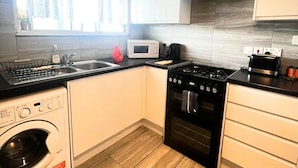 Une cuisine compacte équipée d’un lave-linge, d’un four à micro-ondes, d’une cuisinière et d’un évier.