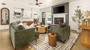 A living room with green armchairs, a wooden coffee table, and a fireplace.