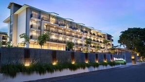 A multi-story hotel with balconies, a well-lit facade, and a landscaped front. - Hilton Garden Inn Bali Nusa Dua (Nusa Dua)
