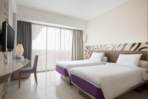 A hotel room with two beds, a desk with a chair, a TV, and a large window with curtains. - Hilton Garden Inn Bali Nusa Dua (Nusa Dua)