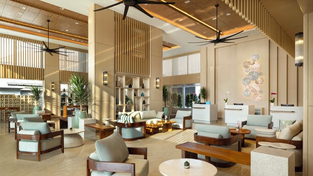 A spacious lobby with multiple seating areas, ceiling fans, and a decorative wall. - Hilton Garden Inn Bali Nusa Dua (Nusa Dua)