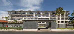 Un hotel de varios pisos con balcones, una entrada protegida por una reja y un cielo despejado.