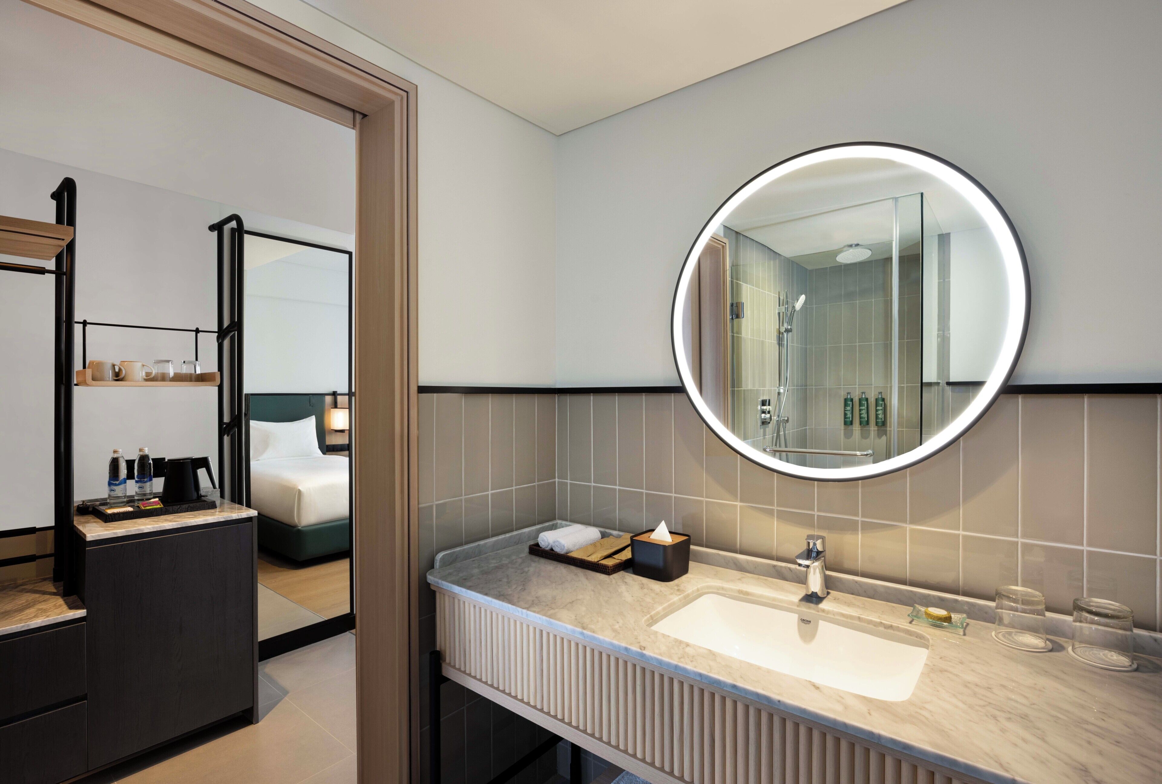 A modern bathroom with a round mirror, a sink, and a shower.